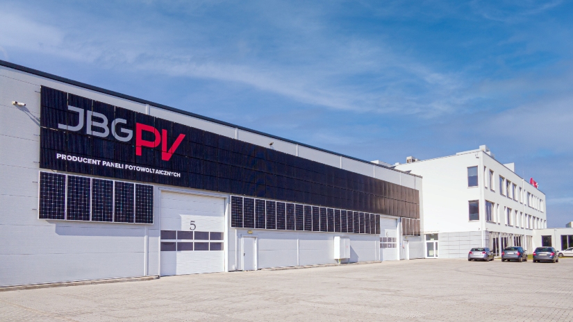 Przyznanie miejskiej nagrody Phoenix Sariensis to swoisty „znak jakości”, gdyż to prestiżowe wyróżnienie trafia tylko do najbardziej wyróżniających się firm, osób i instytucji w naszym mieście. Przykładem na to, że laureaci „Feniksów” świetnie radzą sobie nawet w trudnych sytuacjach jest firma JBG-2 Sp. z o.o. To jeden z większych pracodawców w okolicy, który wciąż się rozwija, rozszerzając swoją działalność o coraz to nowe branże.   Od 2001 roku, kiedy powstała fabryka profesjonalnych urządzeń chłodniczych wiele się wydarzyło – zakład aż trzy razy był rozbudowywany, uruchomiono kompleks laboratoryjny i linię do produkcji systemów oświetleniowych LEDIt. Firma weszła też na rynek kriogeniki, stale inwestując w nowe maszyny. Krokiem milowym było oddanie do użytku drugiej fabryki w Żorach, za czym poszedł także wzrost zatrudnia. Teraz, pomimo panującego kryzysu, firma JBG-2 szuka nowych dróg rozwoju i wprowadziła na rynek kolejną markę – JBGPV, która z miejsca stała się mocnym graczem na rynku instalacji fotowoltaicznych.   - Wydaje się, że z kryzysu jaki dotknął nasze przedsiębiorstwo po pierwszej fali pandemii wyszliśmy obronną ręką. Nowy projekt, związany z odnawialnymi źródłami energii, nie jest pierwszym w naszej historii i doskonale wpisuje się w strategię firmy oraz w oczekiwania rynku – mówi Karol Poremski, dyrektor JBG-2. Na ultranowoczesnej linii produkcyjnej w Żorach powstają najwyższej jakości moduły fotowoltaiczne. To jednak nie wszystko, ponieważ oprócz szerokiego asortymentu paneli fotowoltaicznych JBGPV oferuje także pakiety kompletnych instalacji wraz ich montażem. Wychodząc naprzeciw oczekiwaniom klientów przedstawiciele JBG pomagają także w formalnościach związanych z pozyskiwaniem dotacji oraz w komunikacji z zakładami energetycznymi. - Nie koniec na tym, w ciągu kilku tygodni wprowadzimy do oferty pompy ciepła własnej produkcji – dodaje Karol Poremski.   Postawienie na zieloną energię i ekologiczne rozwiązania to dobry kierunek rozwoju, zwłaszcza biorąc pod uwagę problemy z zanieczyszczeniem powietrza w naszym regionie oraz konieczność wymiany źródła ciepła w wielu budynkach, w związku z tzw. uchwałą antysmogowa. Instalacje fotowoltaiczne są rozwiązaniem coraz chętniej wybieranym przez mieszkańców, ponieważ pozwalają zadbać o środowisko, a przy tym oszczędzić na rachunkach za energię. Można na nie także pozyskać dofinansowanie z Programu Czyste Powietrze.   - Nasza oferta została ciepło przyjęta na lokalnym rynku. Dostajemy sporo zapytań „z polecenia”, co bardzo nas cieszy – mówi Artur Borak, koordynator projektu związanego z fotowoltaiką w JBG-2 Sp. z o.o. - Mieszkańcy regionu chcą inwestować w polskie produkty. Przy tym wspierają też lokalną społeczność, bo zakup instalacji fotowoltaicznej w JBGPV daje pracę znajomemu czy sąsiadowi – dodaje.  Na zdjęciu budynek fabryki JBGPV – biały budynek, z czarnymi panelami fotowoltaicznymi na froncie oraz napisem na czarnym tle JBGPV producent paneli fotowoltaicznych.